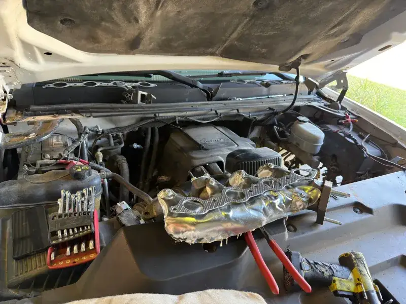 Looking into the engine bay of a Chevrolet Duramax diesel truck with tools on the fender