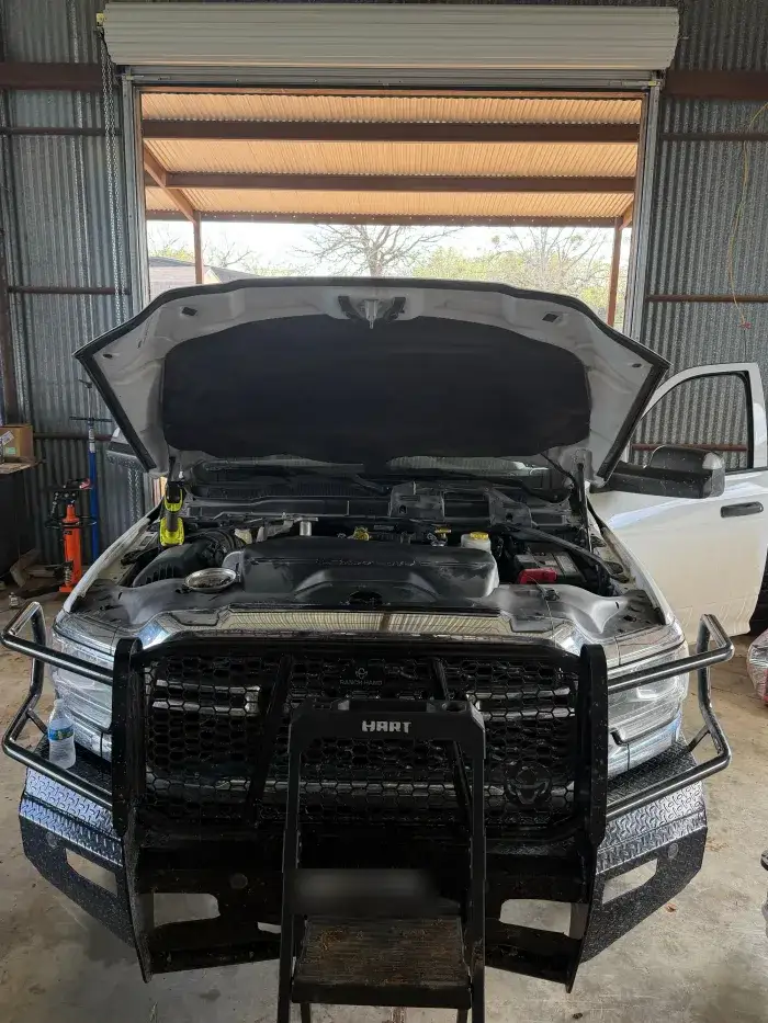 A Ford Super Duty with a grille guard and the hood up