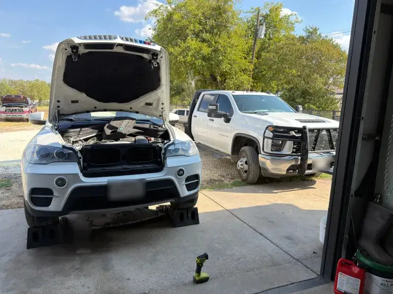 A BMW X5 and a Silverado outside the shop at Young Motorsports with the hood up